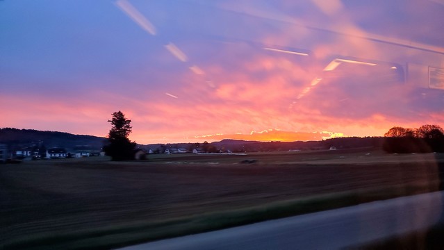 Foto aus dem fahrenden Zug: Brennend oranger Sonnenaufgang