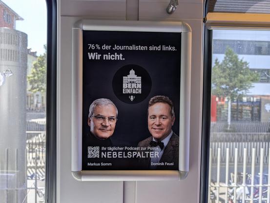 Plakat im Zug (interessanterweise gleich neben der Toilette). Text: "76% der Joirnalisten sind links. Wir nicht. Bern Einfach – Ihr täglicher Podcast zur Politik. Nebelspalter. [Unter zwei Köpfen:] Markus Somm, Dominik Feusi"