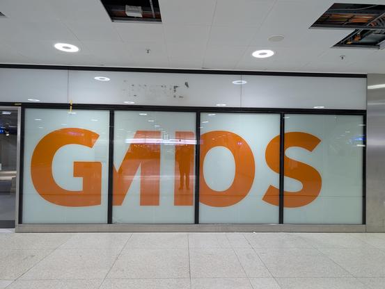 Vier professionell verklebte Schaufenster auf denen in oranger Schrift sowas ähnliches wie "GMOS" zu erkennen ist